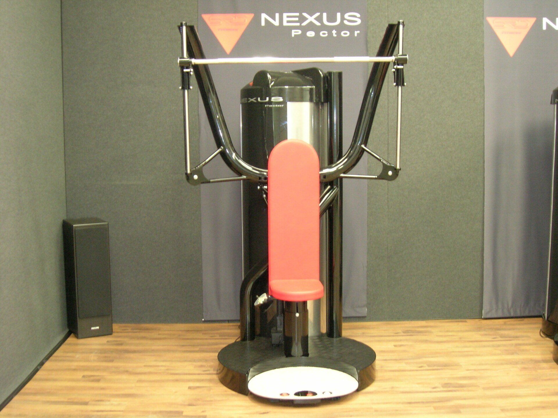 NEXUS fitness machine with red seat and black frame on a wooden floor