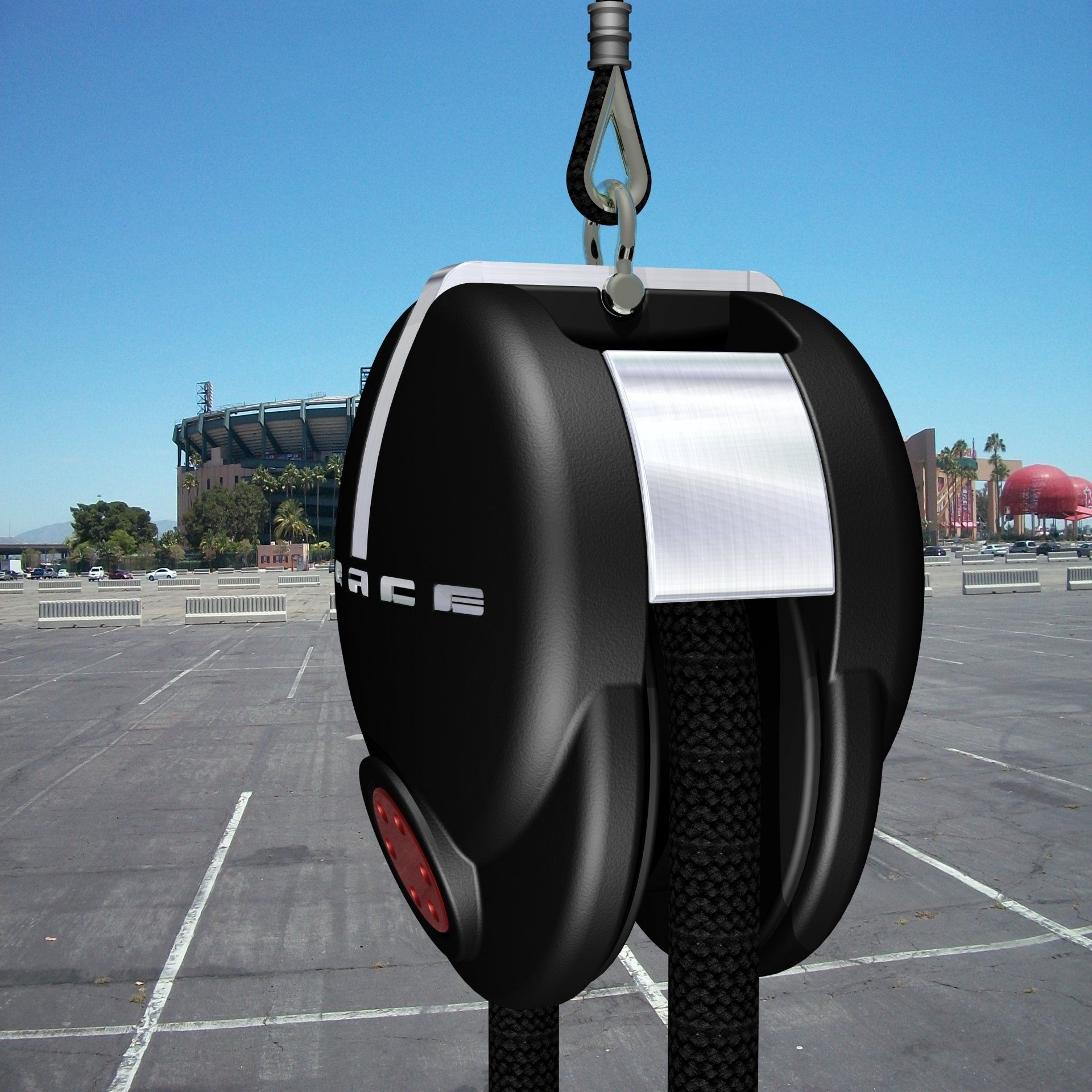 Suspended black-and-silver futuristic device hanging by a hook over an empty parking lot.