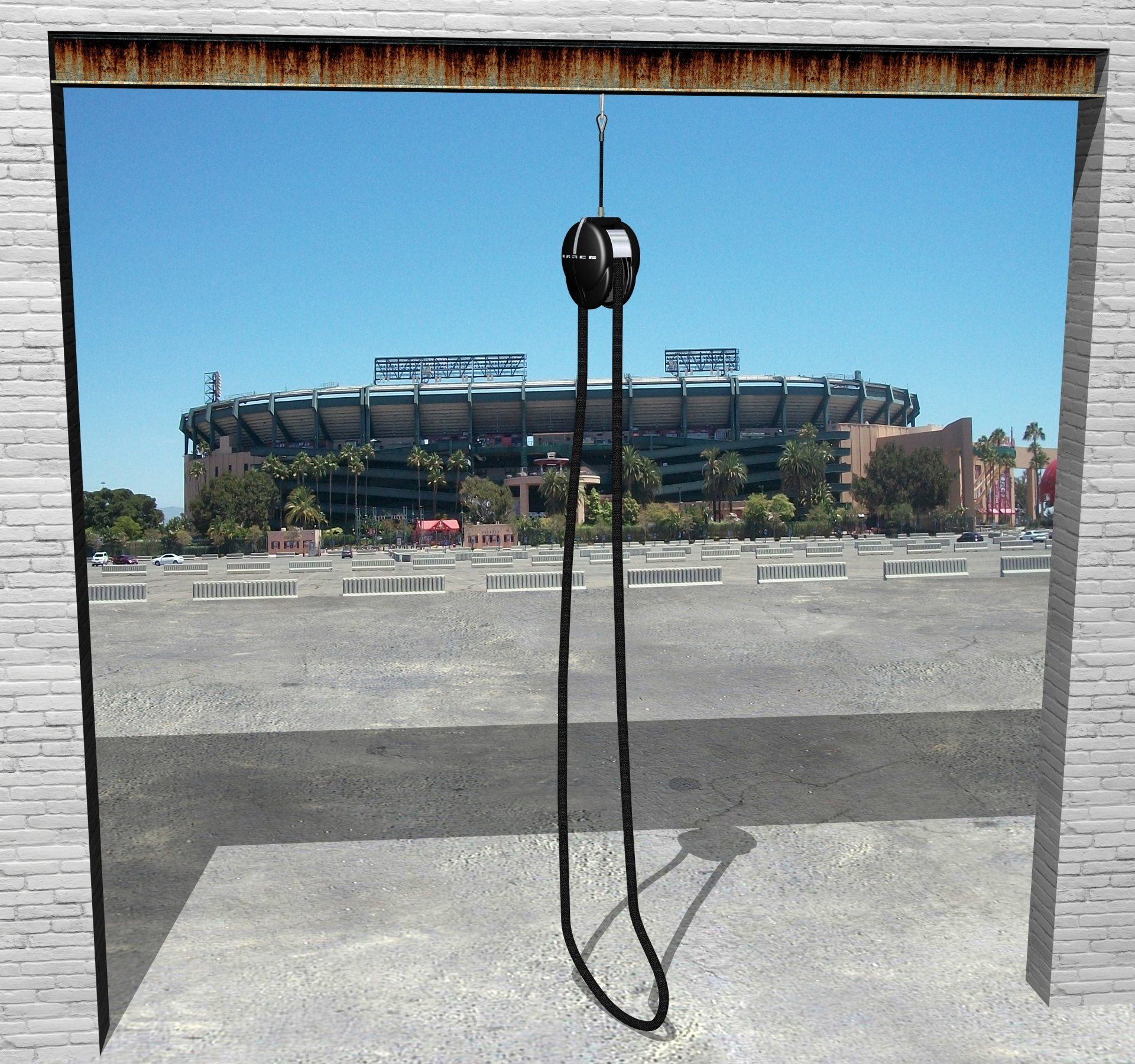 Empty rectangular frame with hanging cable, overlooking a stadium across a parking lot
