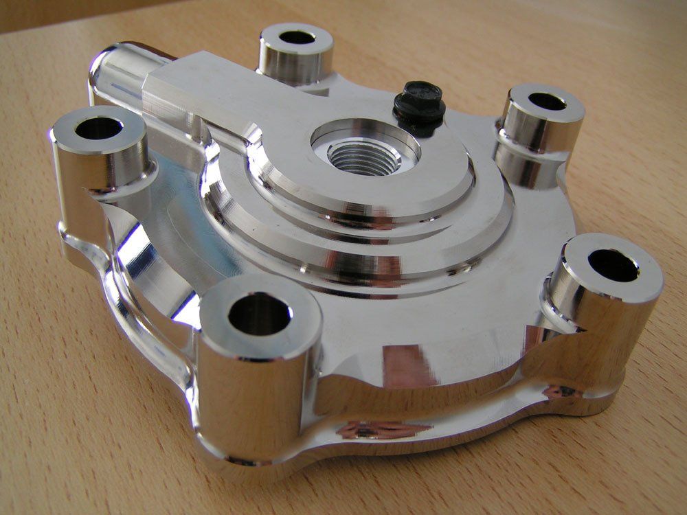 Shiny chrome motorcycle brake disc hub with five mounting posts on a wooden surface