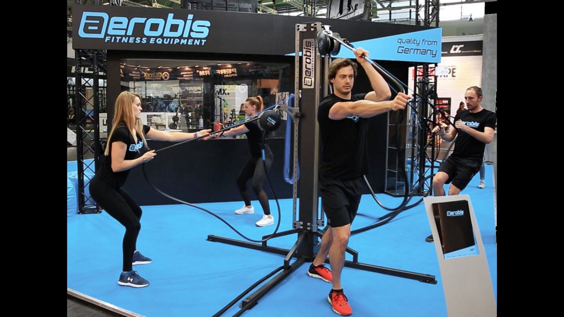 Aerobis fitness booth with people using suspension training equipment at an expo