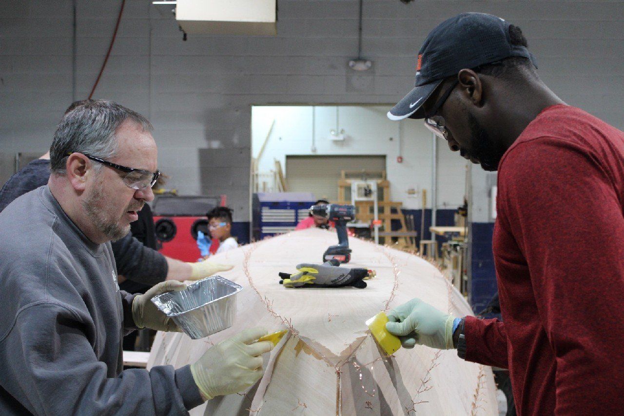Keith and Charles are applying materials to the Row4Kids boat