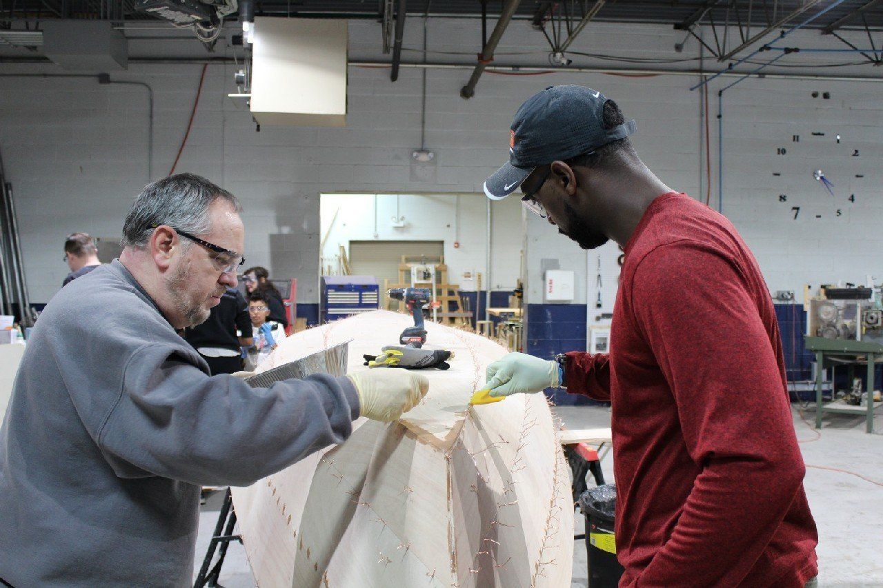 Keith and Charles are applying materials to the Row4Kids boat