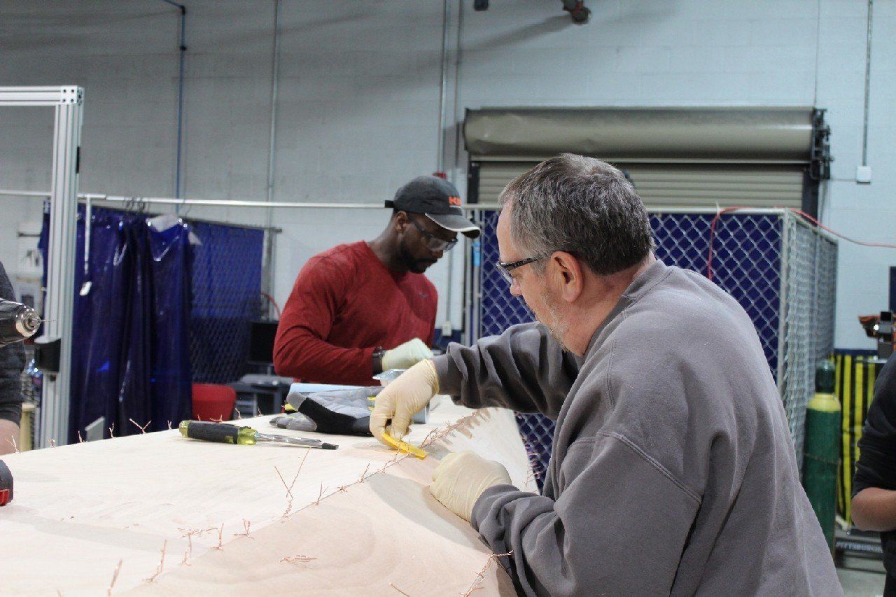 Keith is applying materials to the Row4Kids boat