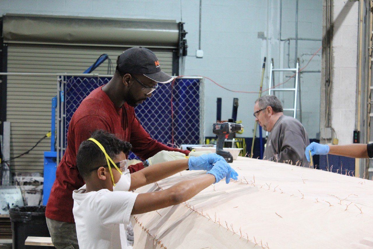 Charles and family are applying materials to the Row4Kids boat