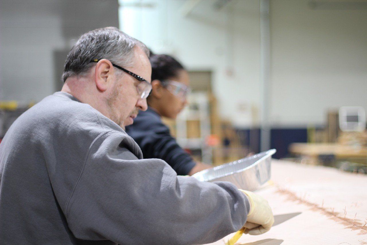 Keith is applying materials to the Row4Kids boat