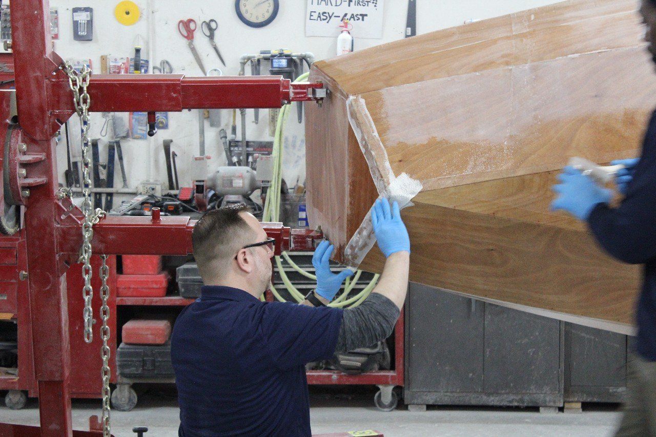 Jake applies materials to the Row4Kids boat