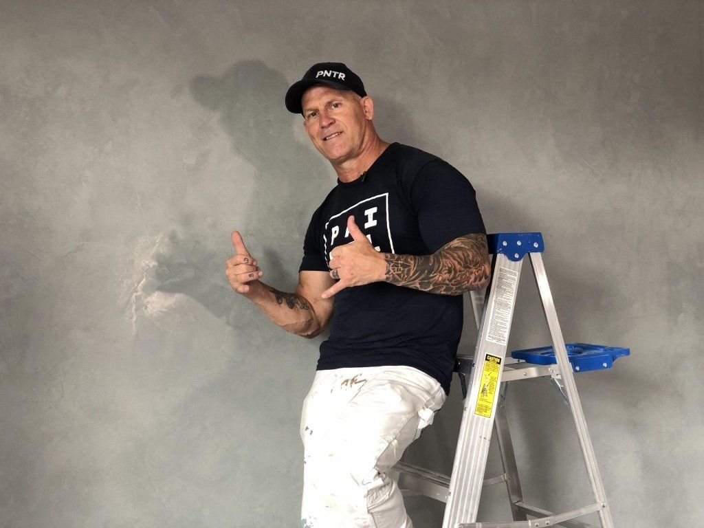 The Idaho Painter is standing on a ladder giving a thumbs up.