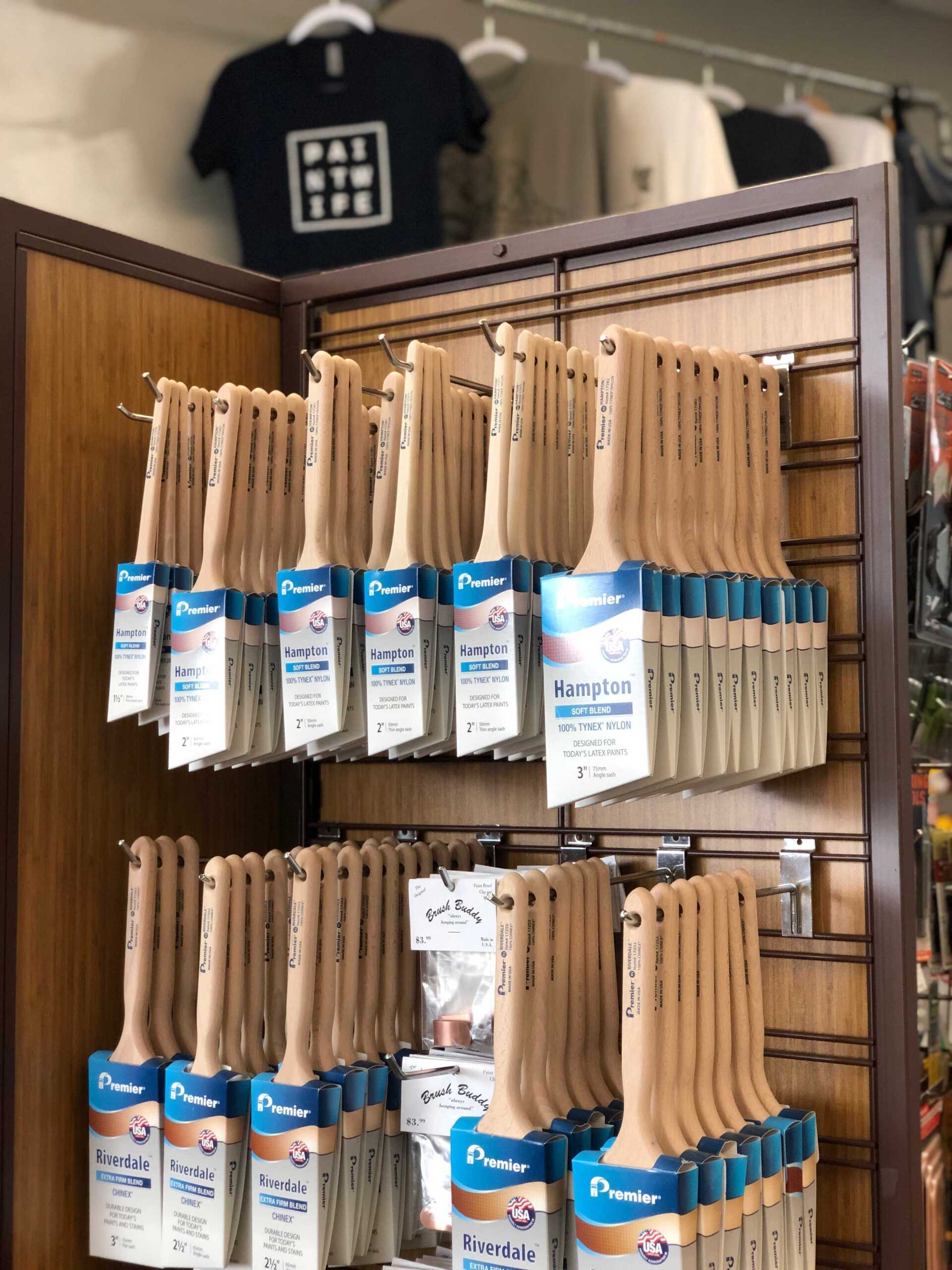 A bunch of Premier hand made paint brushes are hanging on a wall