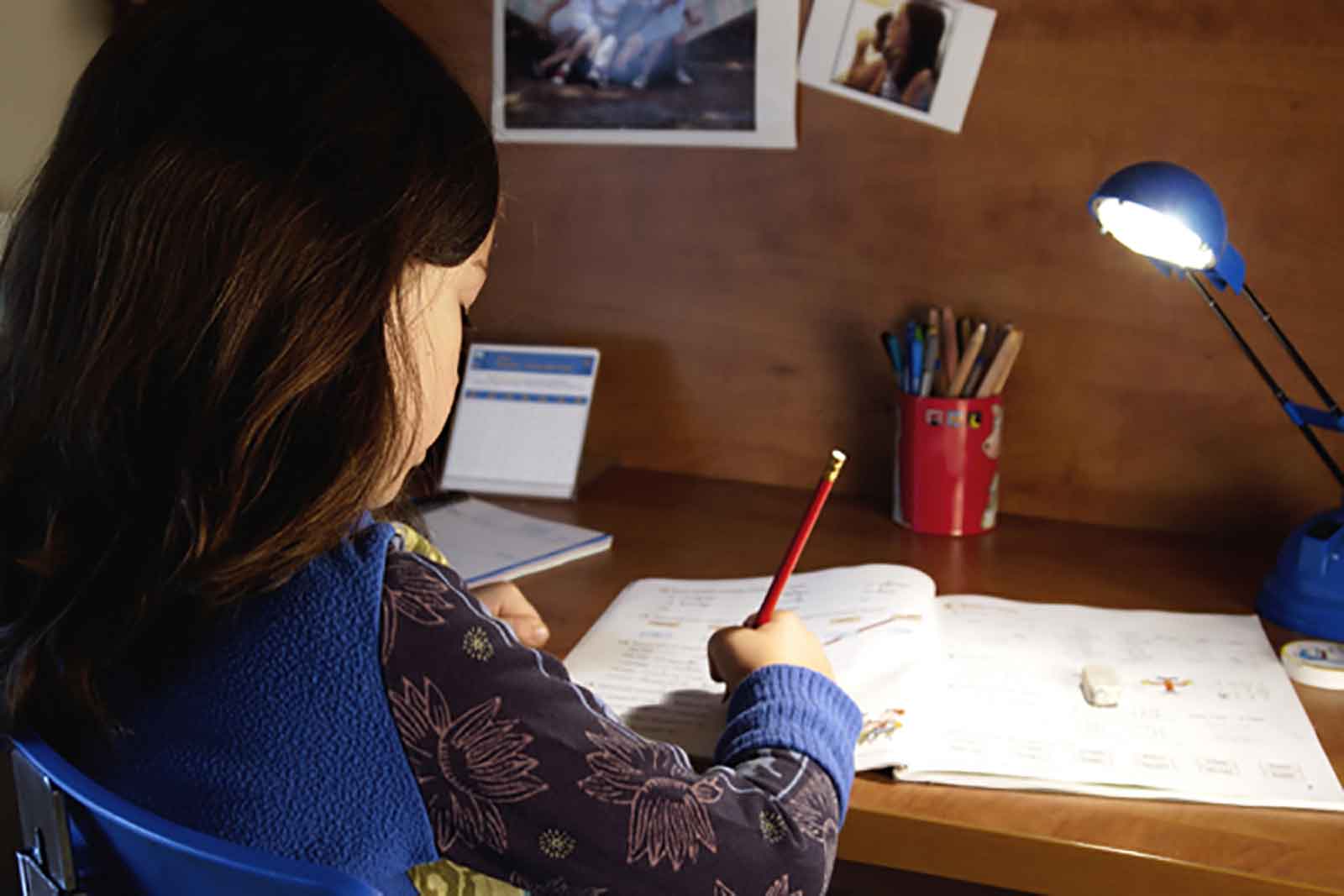 A girl doing her home work with a pencil and paper.