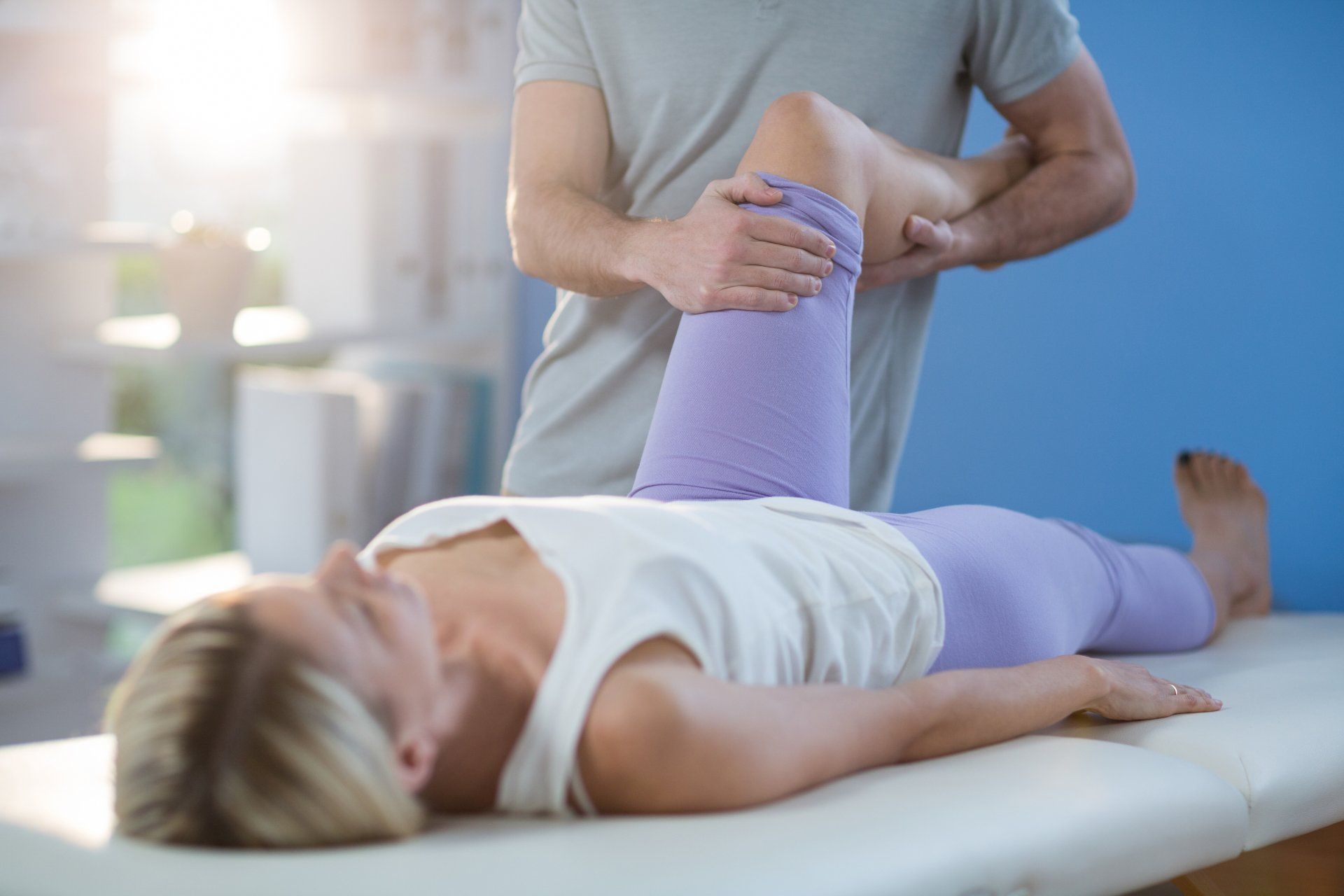 osteopathy cranial - Male physiotherapist giving knee massage to female patient in clinic