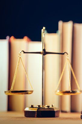 A scale of justice is sitting on a table in front of a row of books.