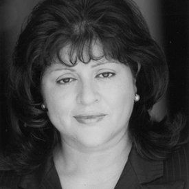 A black and white photo of a woman in a suit and earrings.