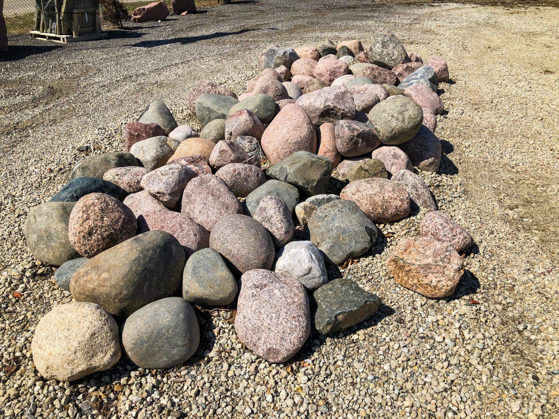 Pile of assorted granite and limestone rocks on a gravel surface.
