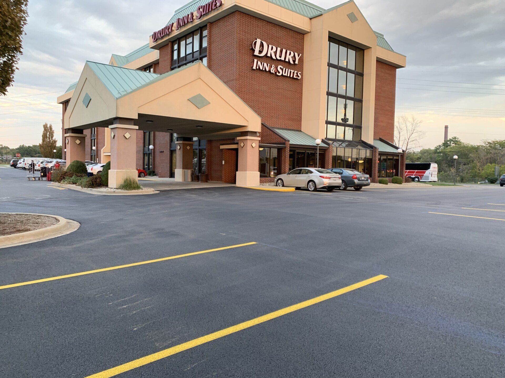 Drury Inn & Suites hotel exterior, brick facade, covered entrance, cars parked in front.