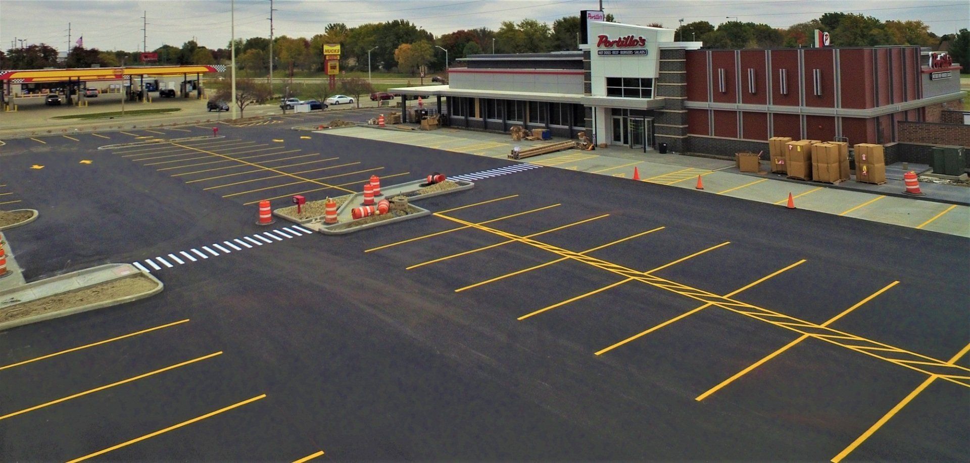 Newly paved parking lot with yellow parking space lines, in front of a building.
