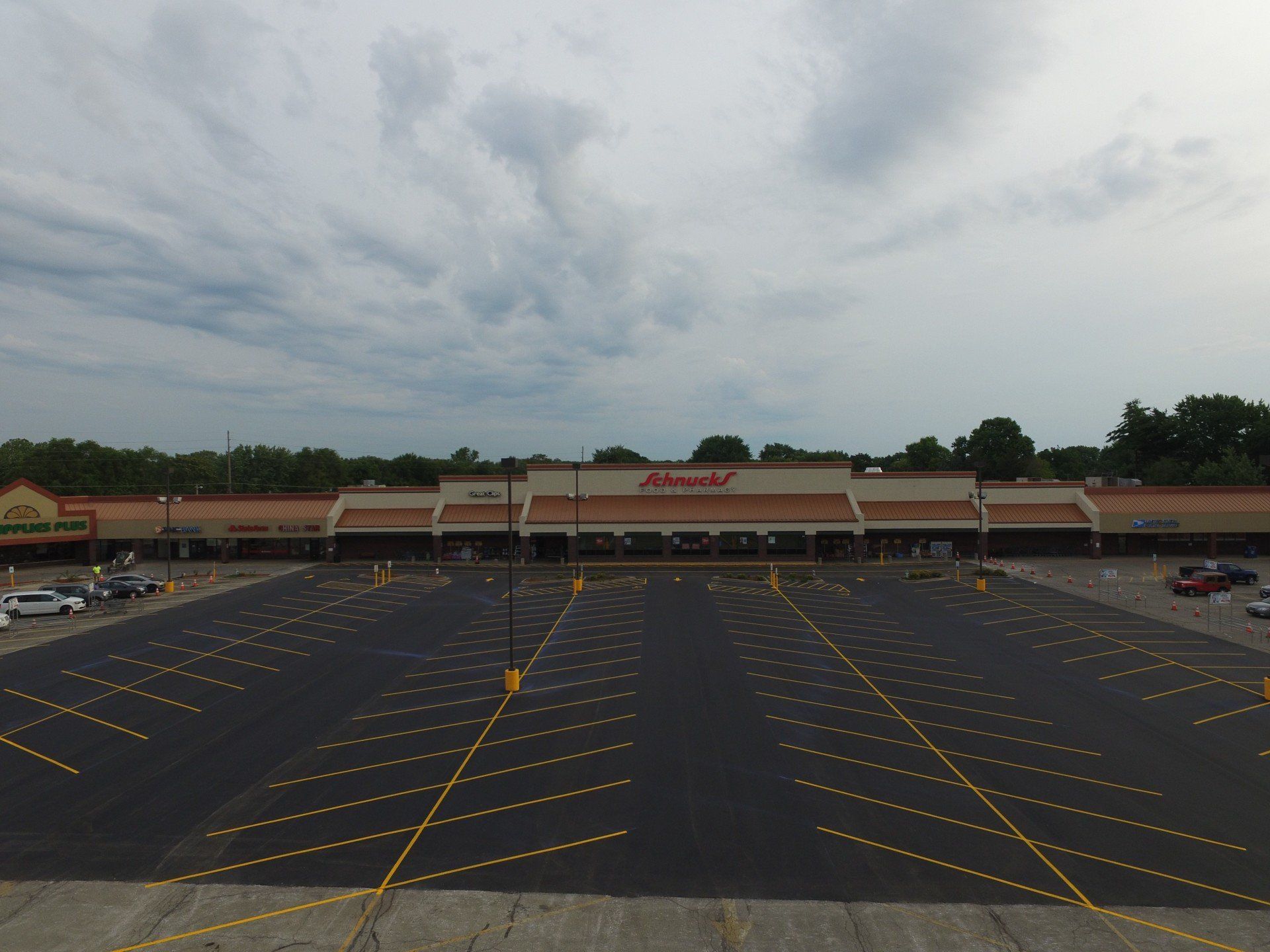 A wide, empty parking lot in front of a supermarket on an overcast day.