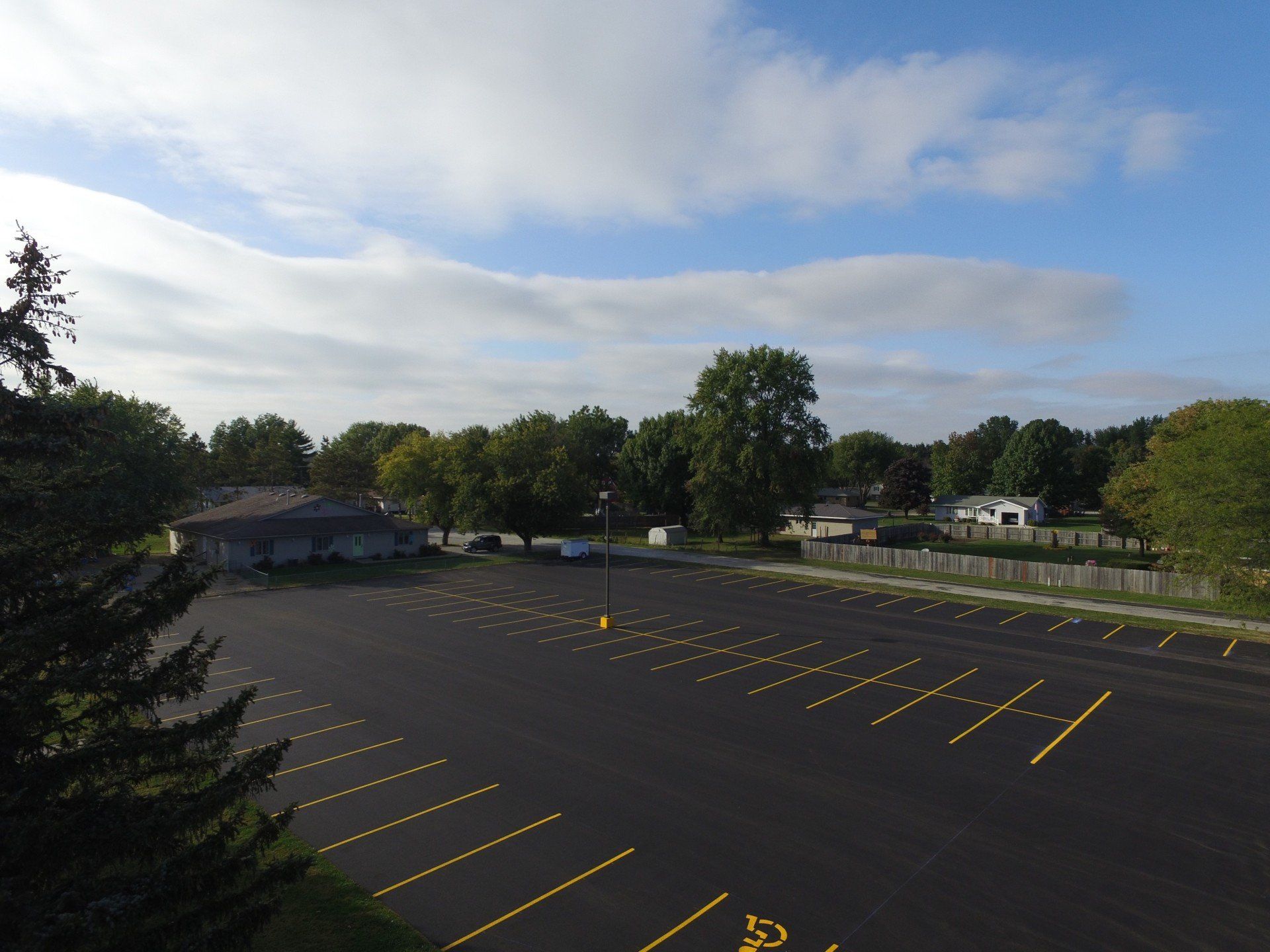 Large, empty parking lot with yellow markings under a blue sky with some clouds.