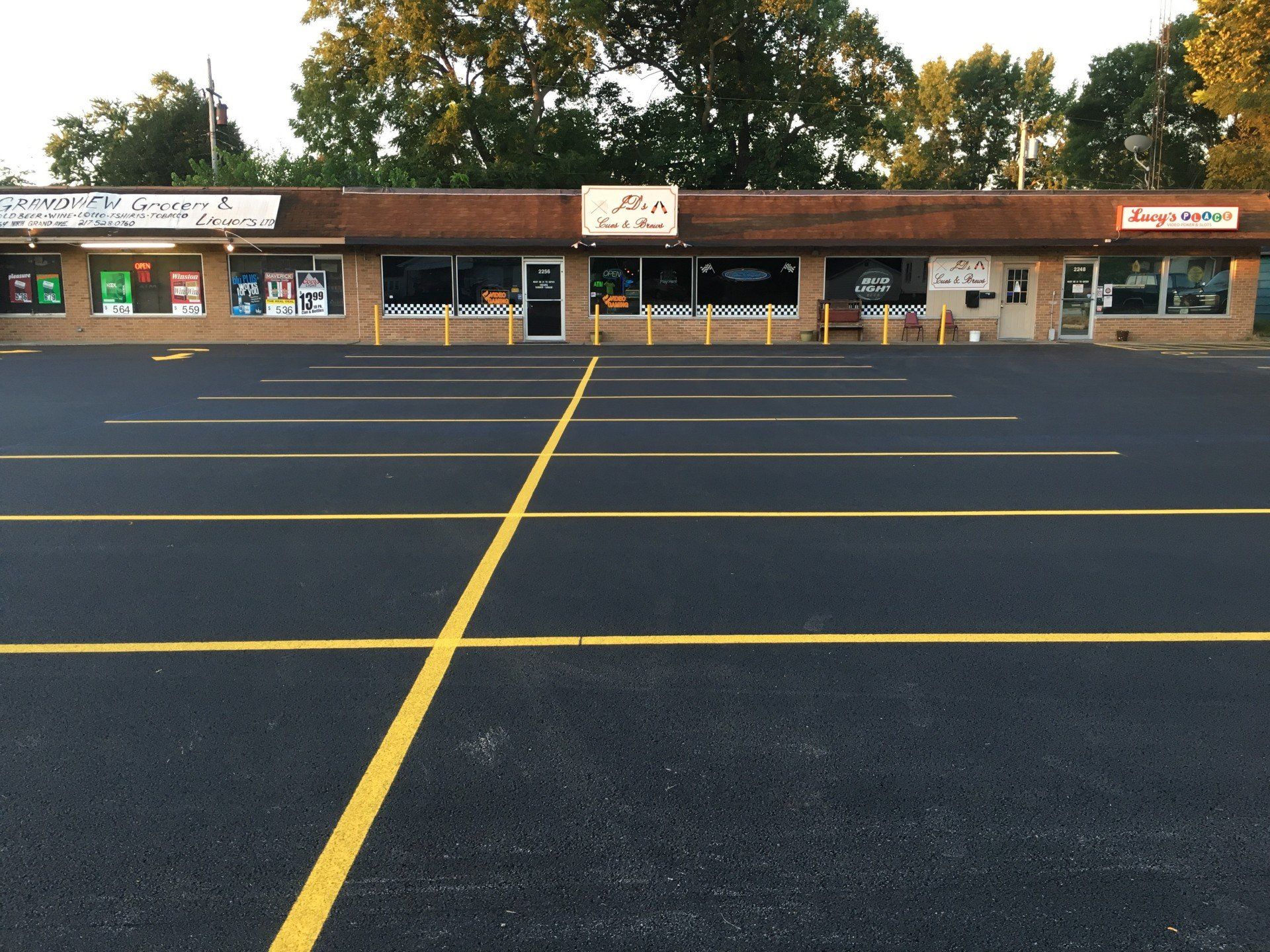 A storefront with a newly paved parking lot. The building has a brown roof and a sign that reads