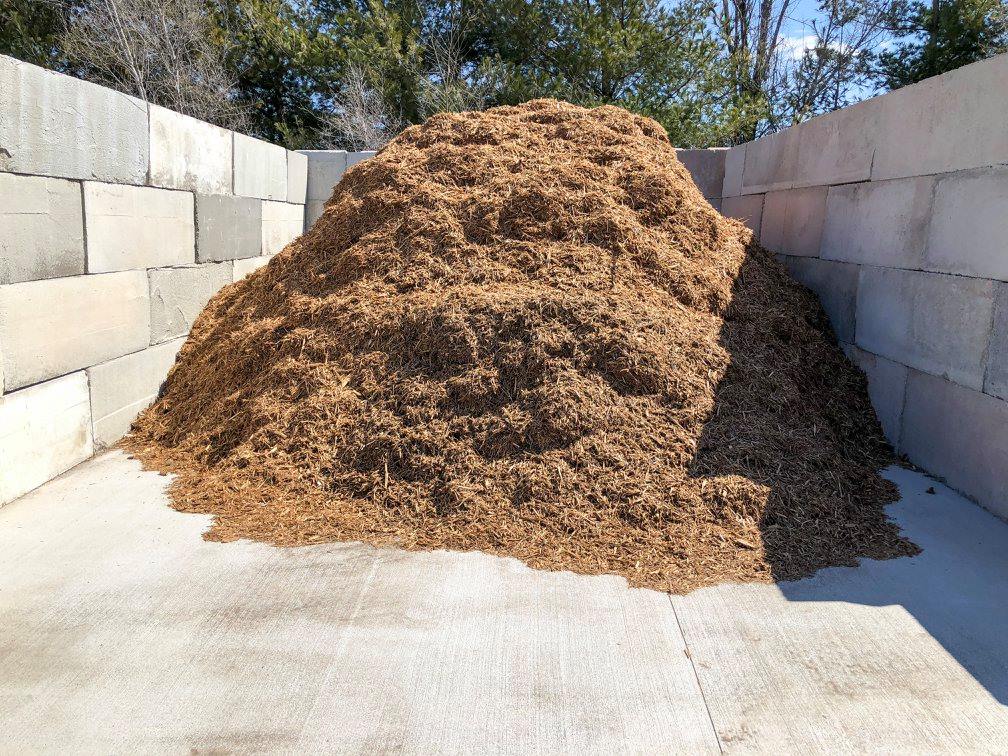 Pile of brown wood chips in a concrete bin.
