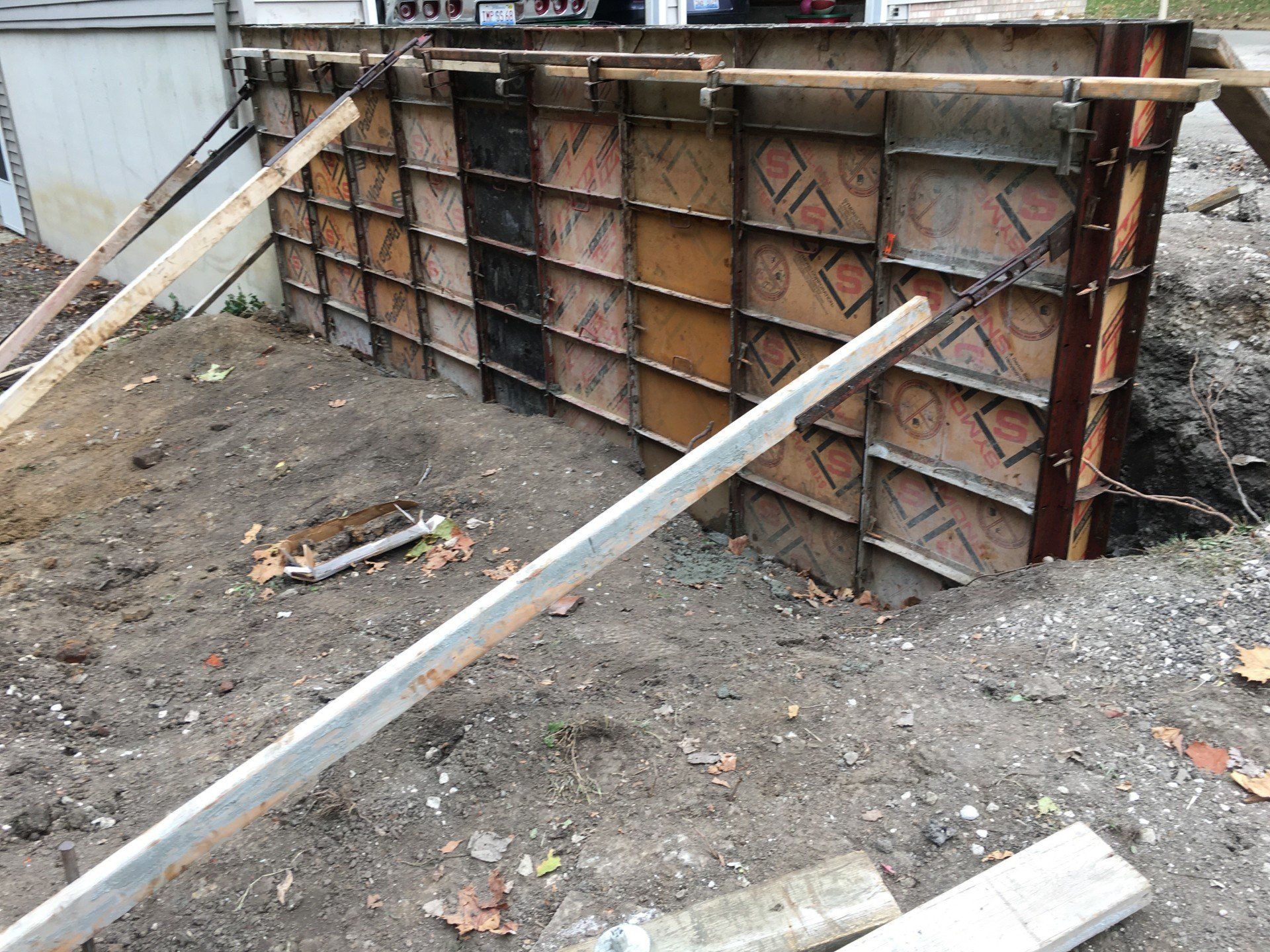 A concrete formwork in an earthen excavation, supported by wooden bracing, ready for pouring.