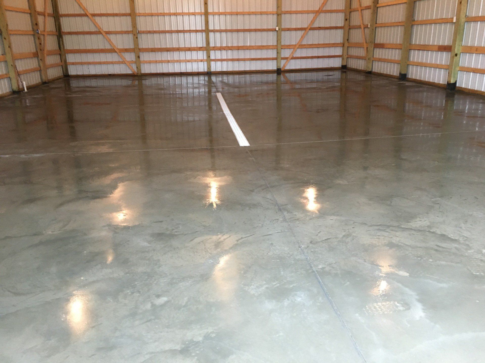 Polished concrete floor inside a wooden-framed building with a white line down the center.