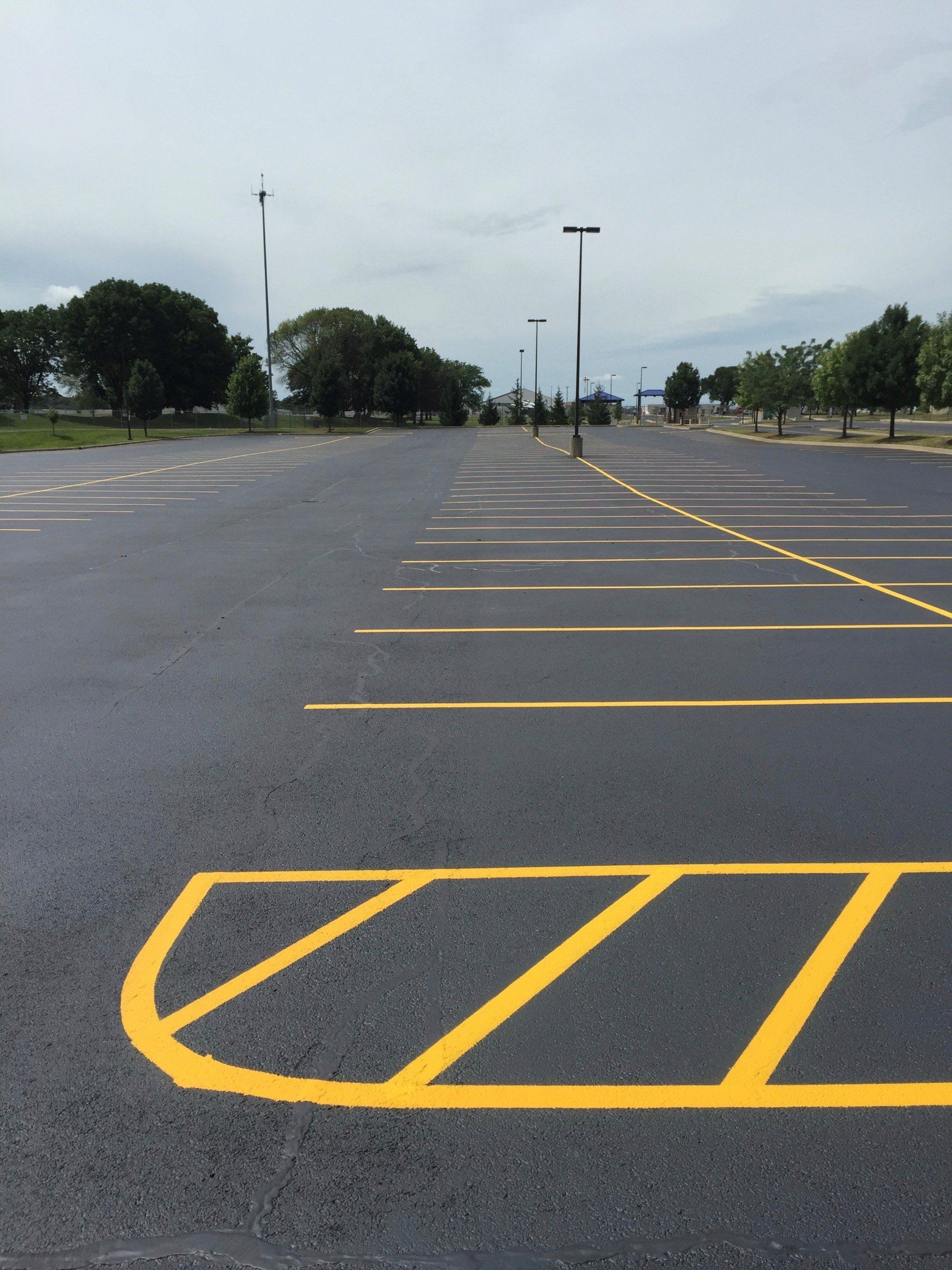 Empty asphalt parking lot with yellow painted parking spaces and a cross-hatched area.