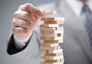 Planning, risk and strategy in business, businessman gambling placing wooden block on a tower