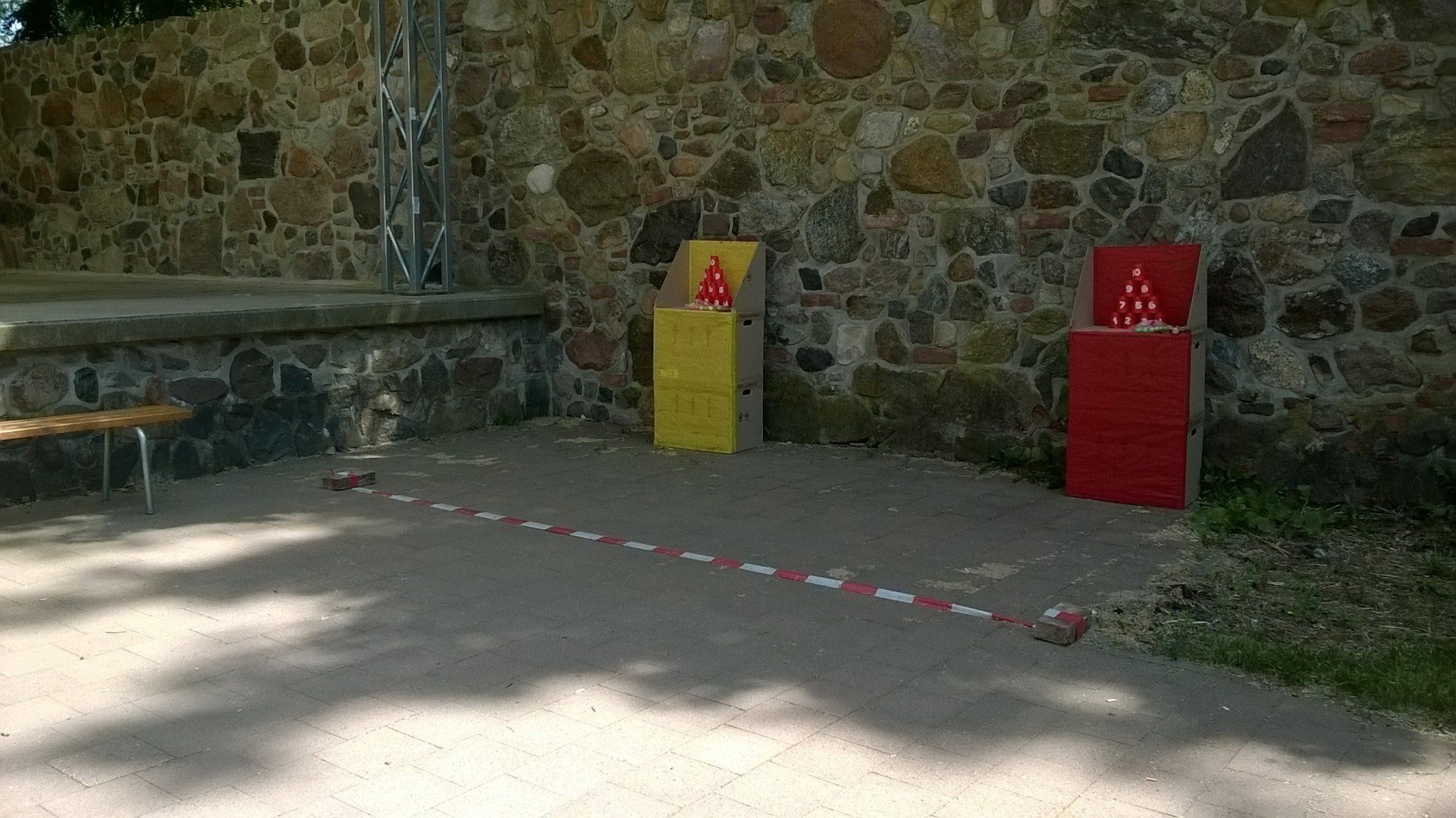 Eine Backsteinmauer mit einer rot-gelben Kiste davor.