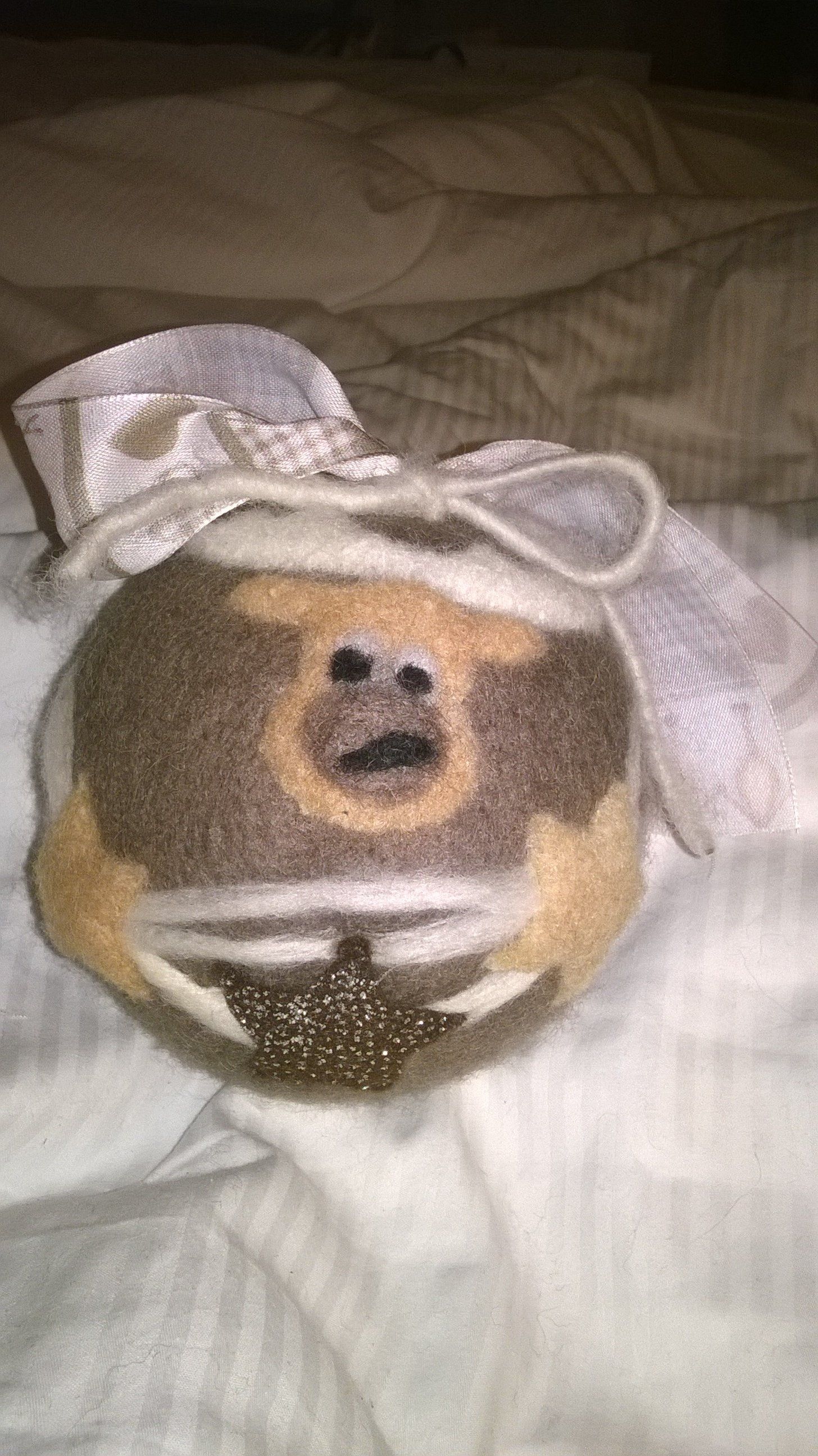 Ein Stofftier mit einer Schleife sitzt auf einem Bett.