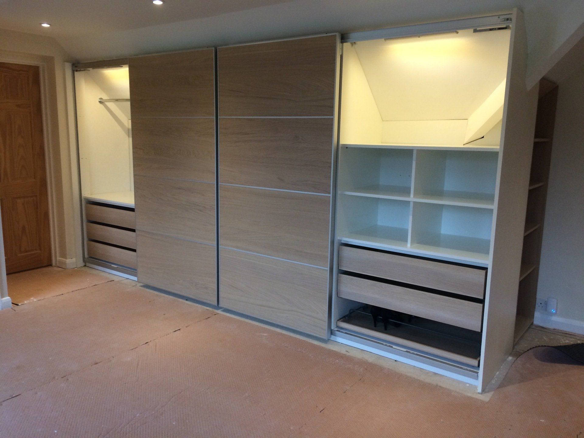 A wardrobe made using Ikea sliding doors and drawers. Fitted in a loft conversion with sloping ceilings.