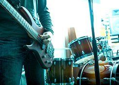 A guitarist standing in front of a drum kit