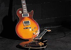 A guitar on the floor in front of a guitar standing upright