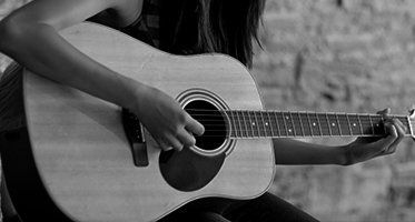 A long haired lady playing acoustic guitar