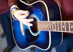 A man playing a blue acoustic guitar