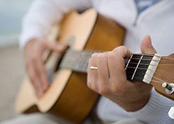 A man in a white shirt, playing acoustic guitar