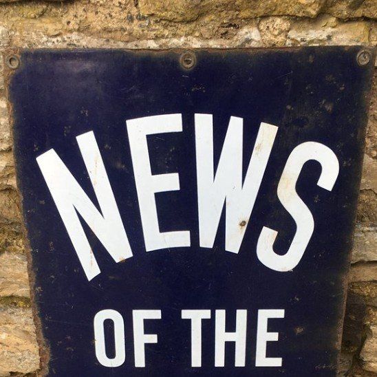 black sign with white writing saying NEWS,