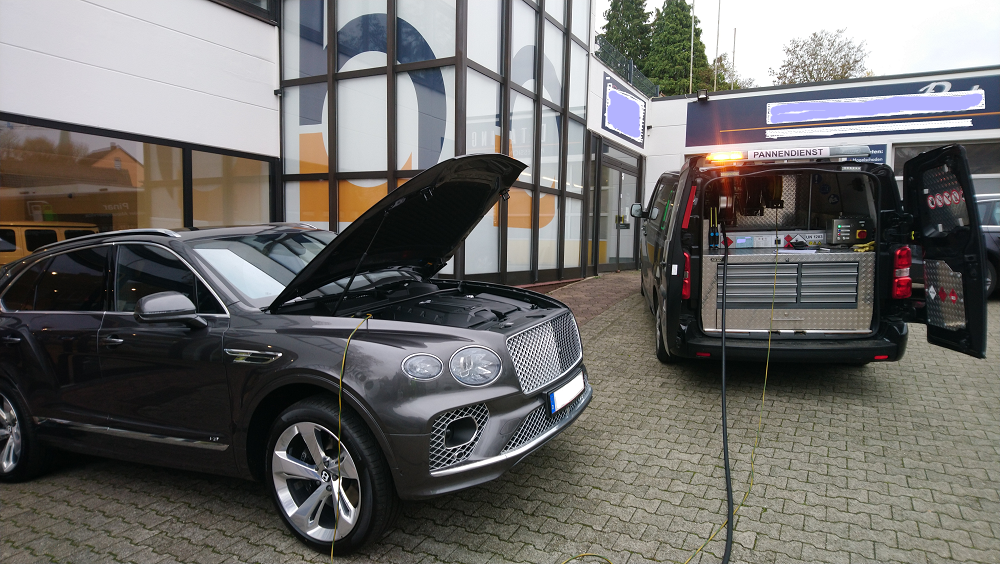 Ein Bentley steht mit geöffneter Motorhaube vor einem Gebäude, falsch getankt - Kraftstoff wird abgesaugt.
