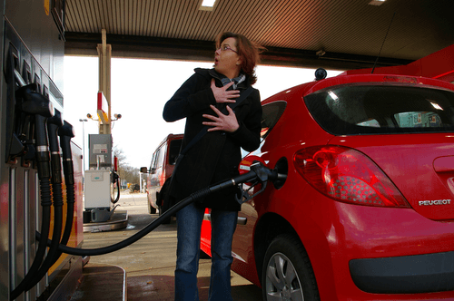 Eine Frau pumpt Benzin in ein rotes Auto an einer Tankstelle, falsch getankt - Kraftstoff wird abgesaugt.