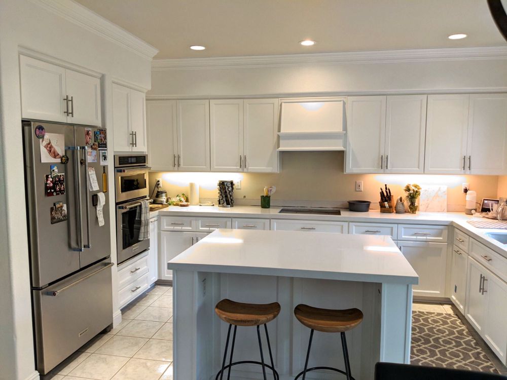 A kitchen with white cabinets , stainless steel appliances , and a large island.