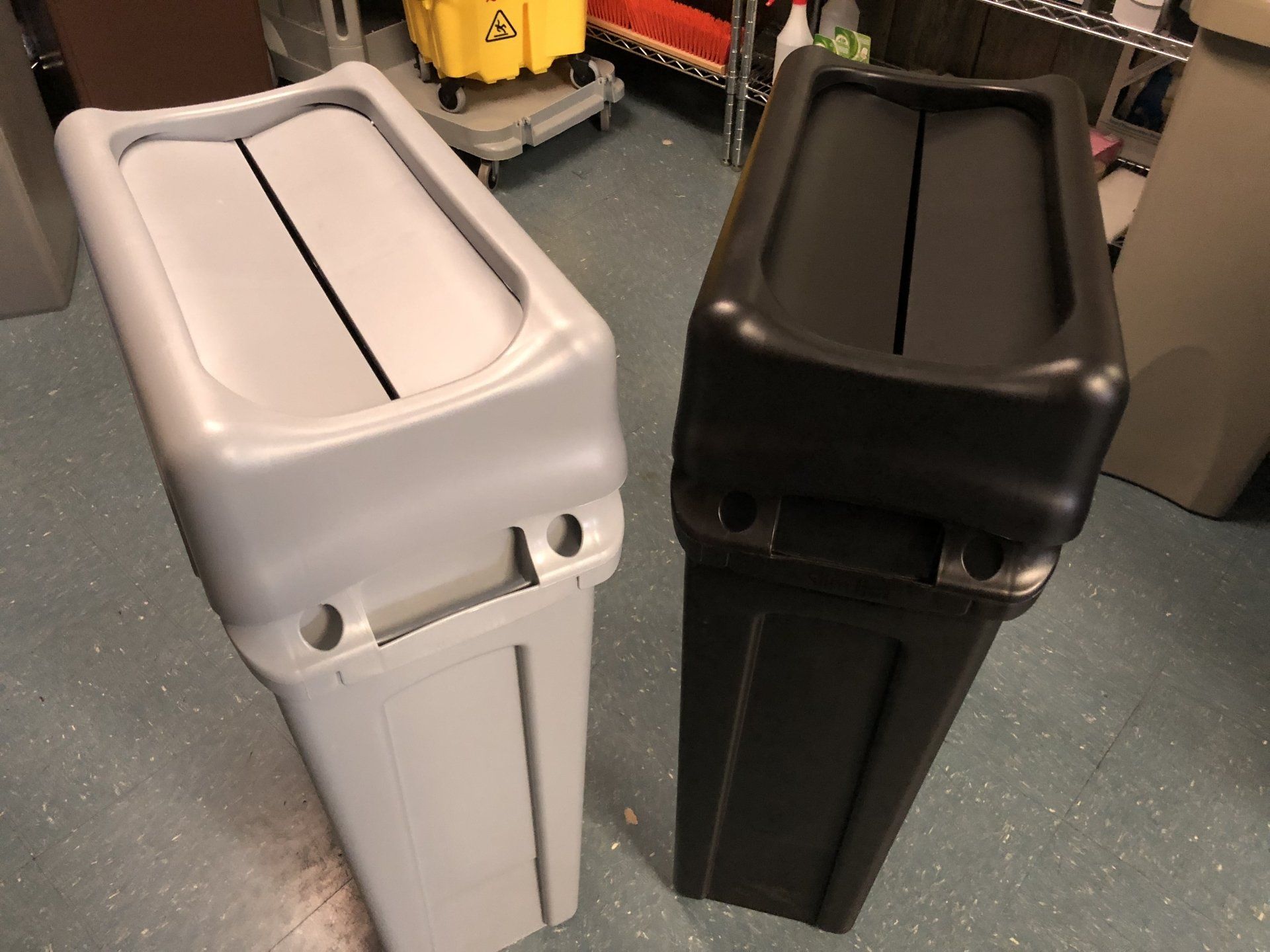 Two trash cans are sitting next to each other on the floor
