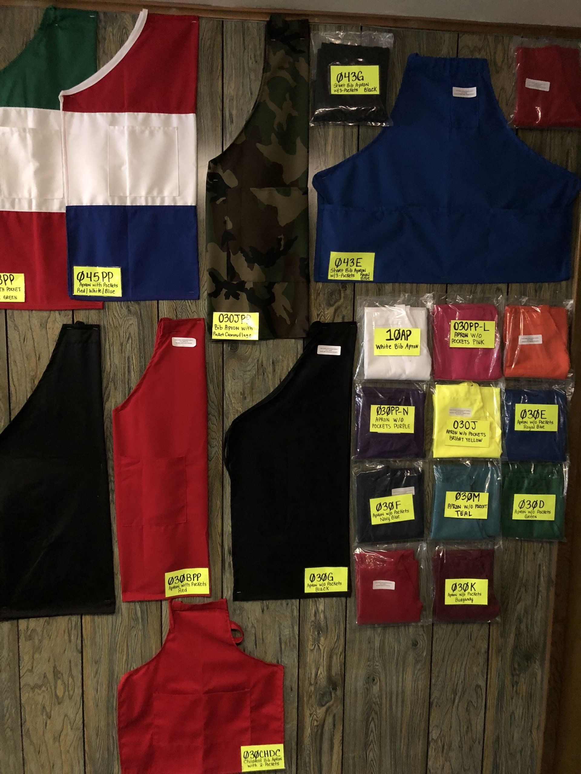 A bunch of aprons are hanging on a wooden wall