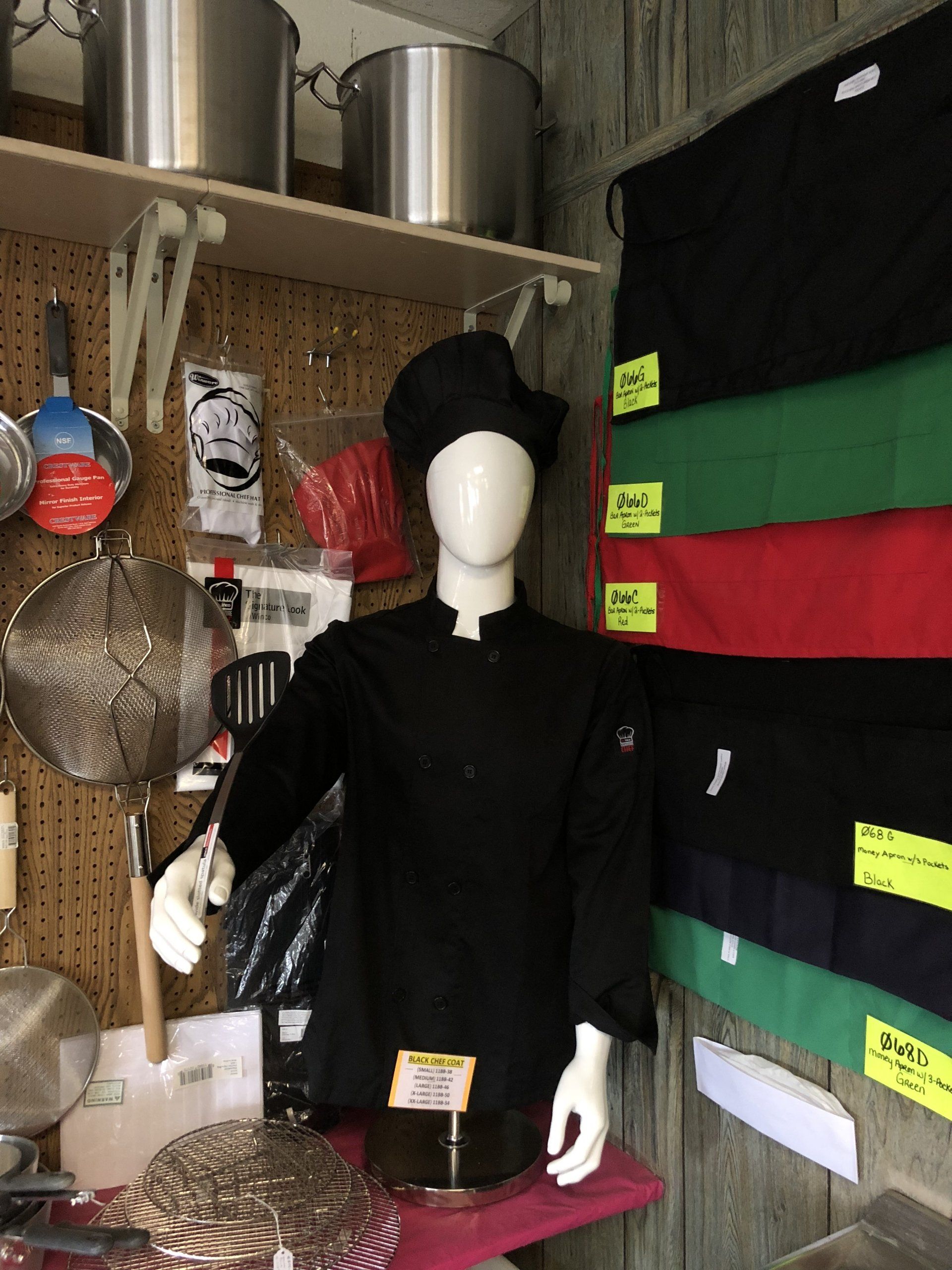 A mannequin wearing a black chef 's jacket and hat