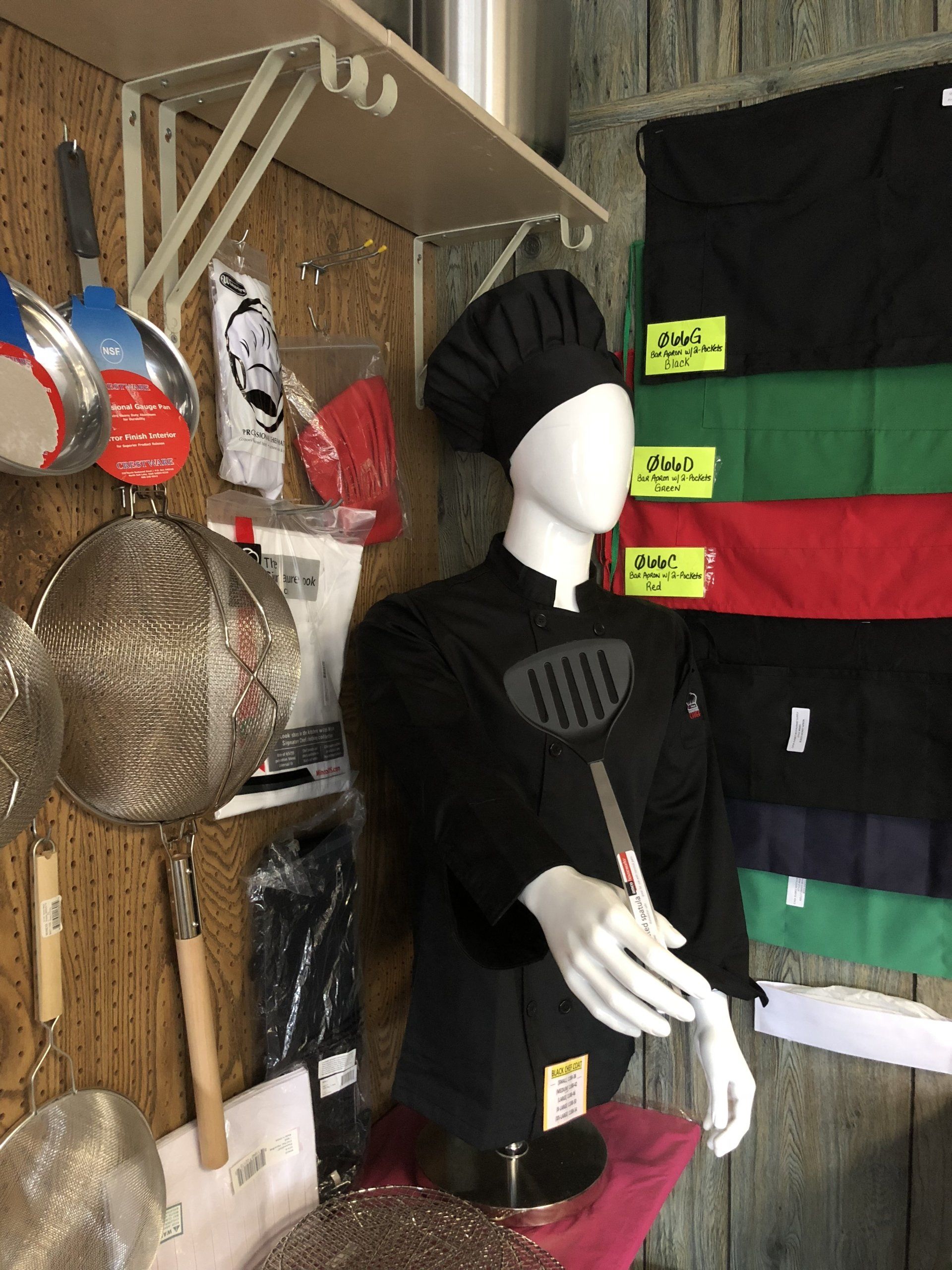 A mannequin wearing a black chef 's jacket and hat