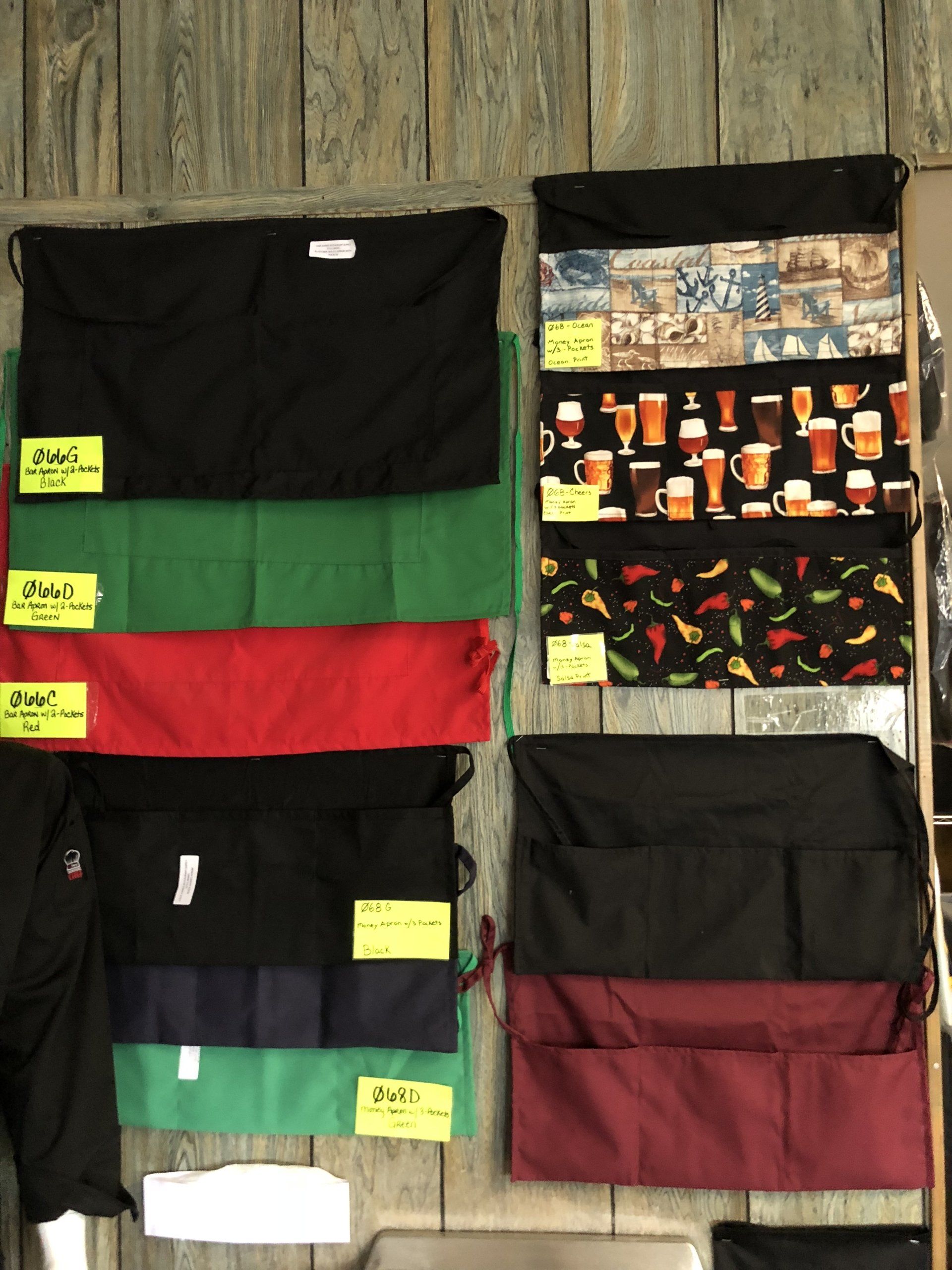 A bunch of aprons are hanging on a wooden wall