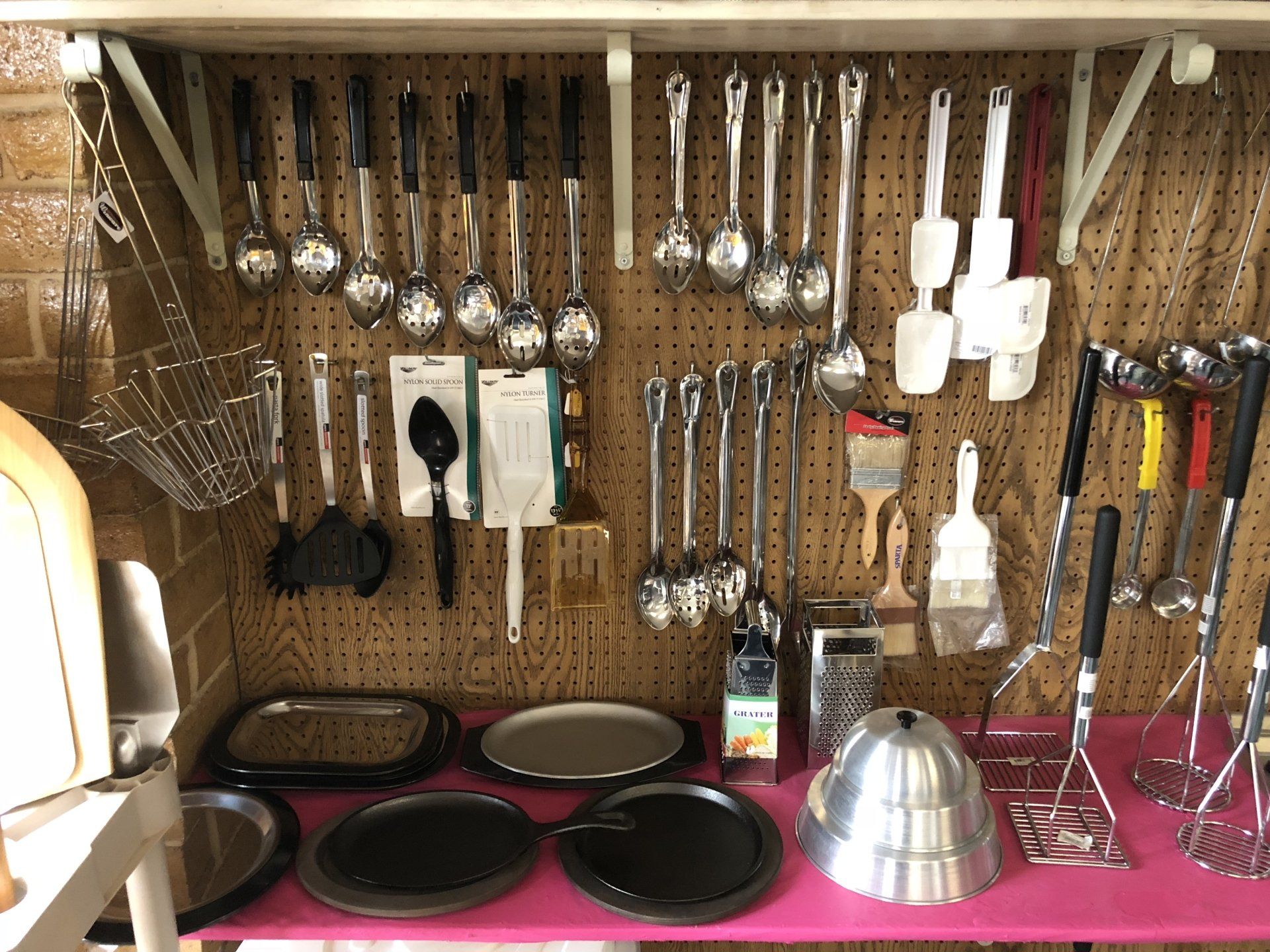 A bunch of kitchen utensils are hanging on a wall