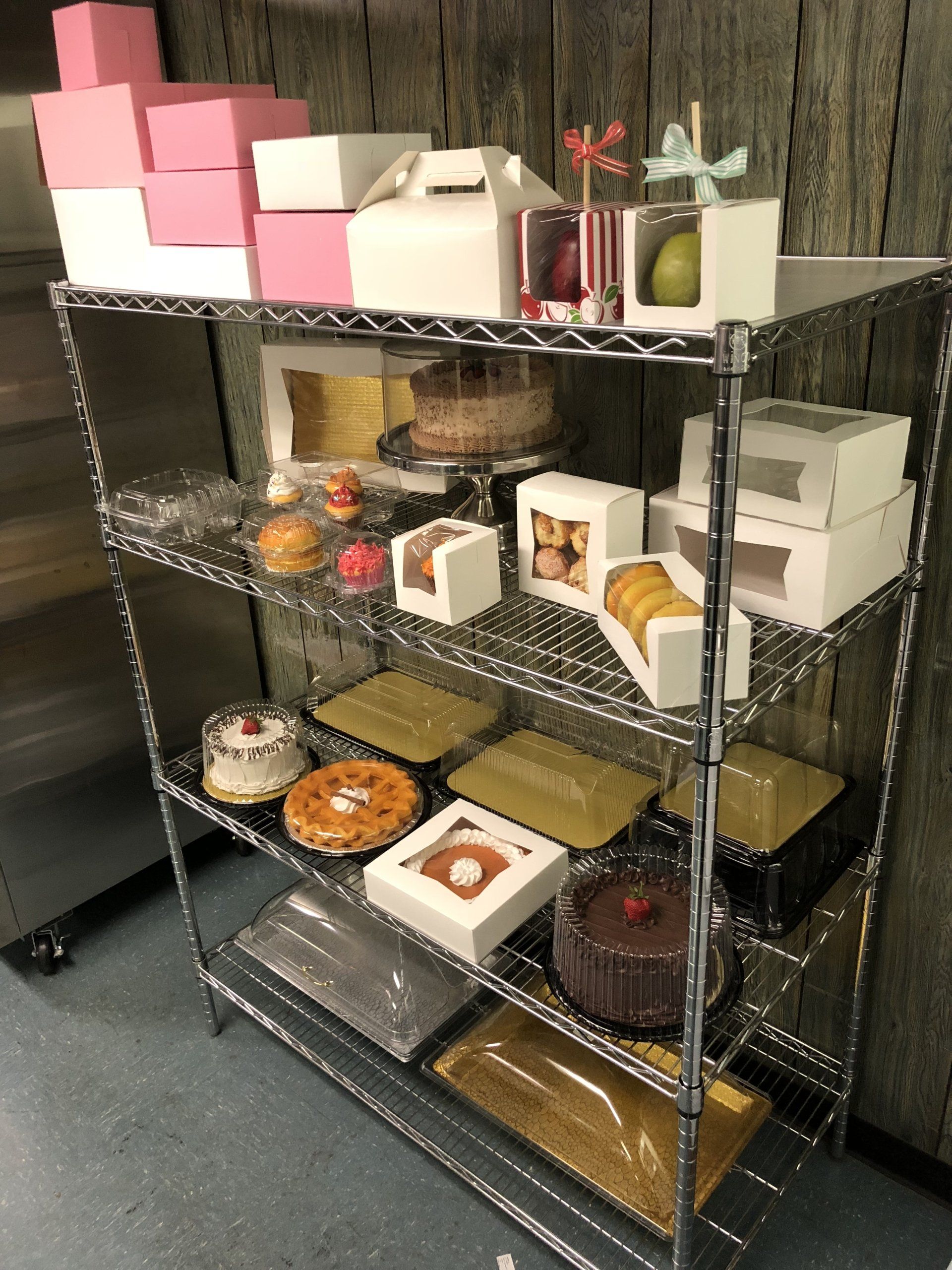 A metal shelf filled with different types of cakes and boxes