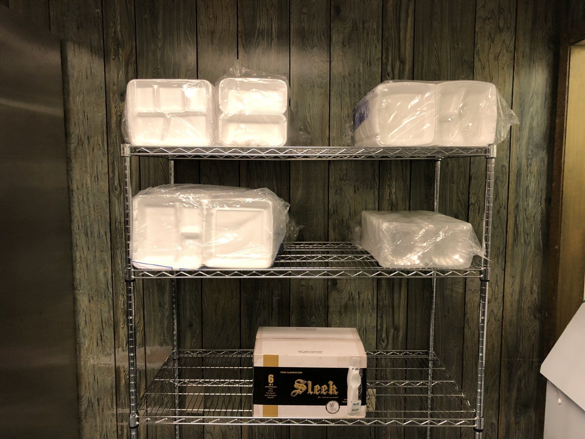 A metal shelf with styrofoam containers and a box that says steak on it