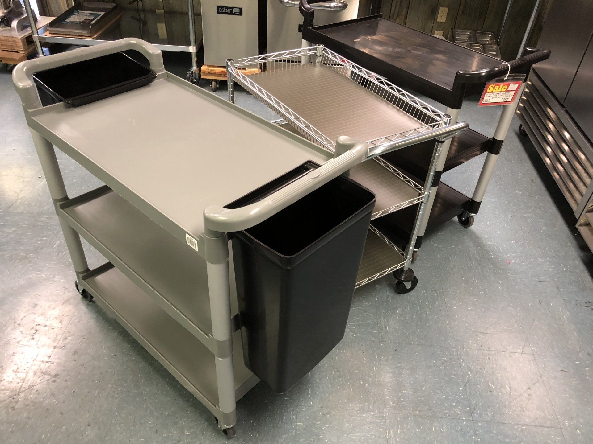 A trash can is attached to a cart in a kitchen.