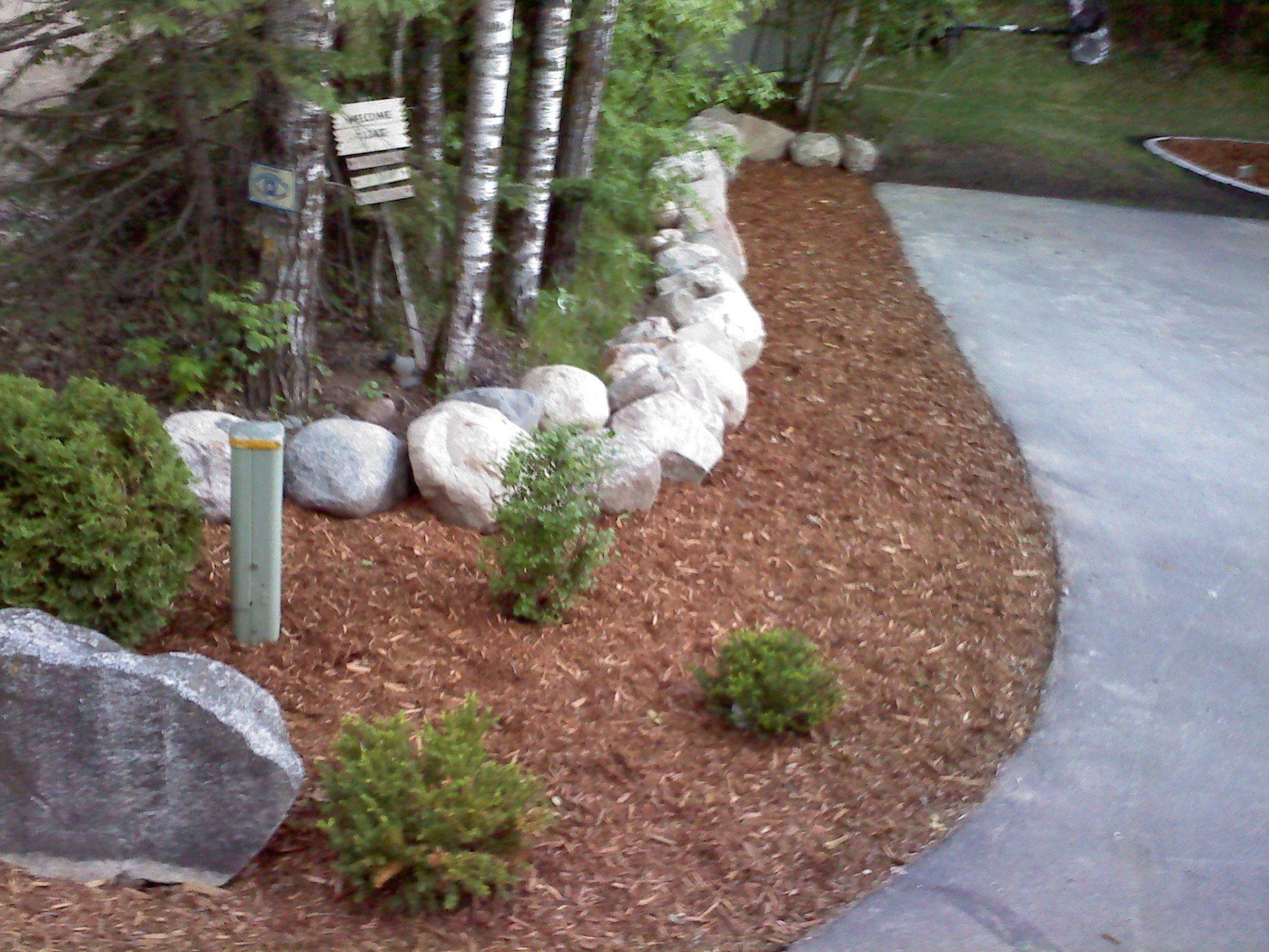 A driveway with rocks and mulch on the side of it